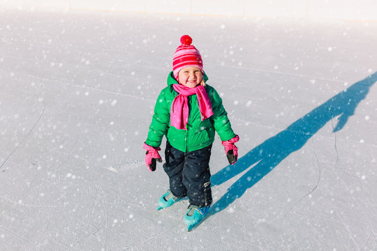 happy little girl learning to skate in winter