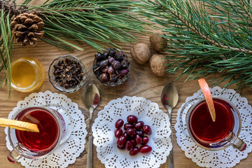 Two glass of mulled wine with cinnamon sticks, slice of oranges and apple, star anise on a wooden table