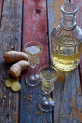 Homemade ginger tincture or ale on wooden background. Rustic style. Spice yellow liqueur in a glass. Alcohol drink.