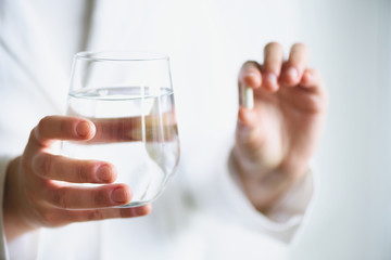 Doctor holding a glass of water with drug, pills, white background. Copy space. Medicine concept.