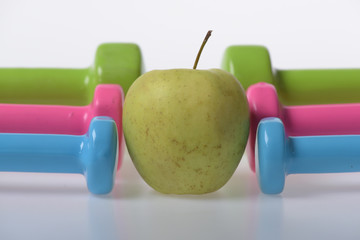 Apple fruit between pink, blue and green barbells in pattern
