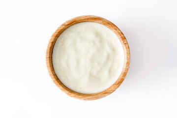 Natural yogurt in wooden bowl isolated on white background. Top view 

