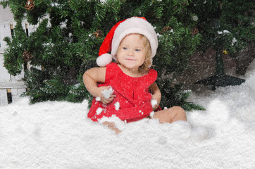 smiling girl in santa costume sits on snow