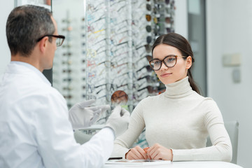 Obraz premium partial view of optometrist showing lens to patient in optics