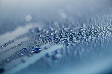 Close-up of water drops on the metallic surface of a blue car at auto wash