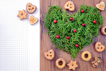 Christmas bakery copy space background with cookies and heart of pine twigs with red fruits