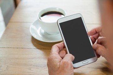 Close up of senior person holding smart phone while sitting at