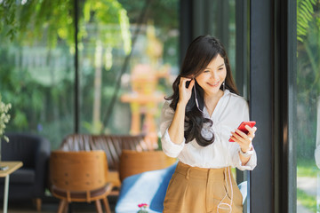 Young beautiful asian woman listening to music from smartphone while relax in cafe with happiness