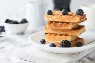 Waffles on a white plate decorated with blueberries with marbled background. copy space