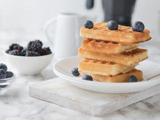 Waffles on a white plate decorated with blueberries with marbled background. copy space