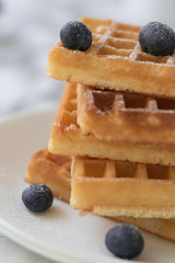 Waffles on a white plate decorated with blueberries with marbled background. copy space