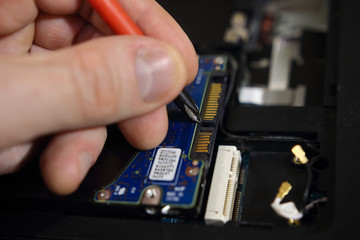 Repair of computers in service center close-up. Disassembly of laptop by engineer. Setting up electronics.