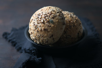 Bread rolls with pumkin seeds and sunfliwer seeds in a back plate with a  dark rustic background.