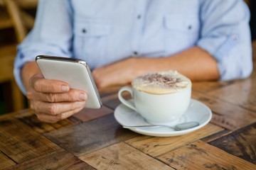 Cropped image of person holding smart phone while sitting by