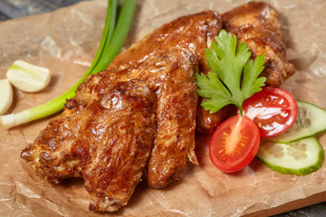 Crispy baked chicken wings on wooden board, closeup