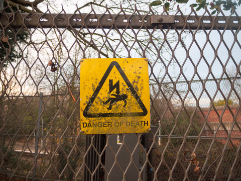 danger of death yellow rusty dirty unclean sign on metal fence lightning bolt