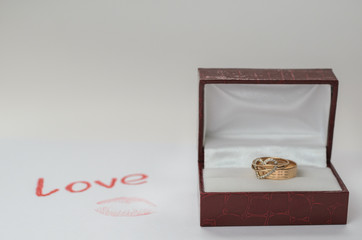Still Life for Valentine's Day. Gold rings in a dark red box for jewelry, a love letter and a kiss imprint on paper.