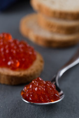 Caviar vermelho russo em uma colher e torradinha de pão