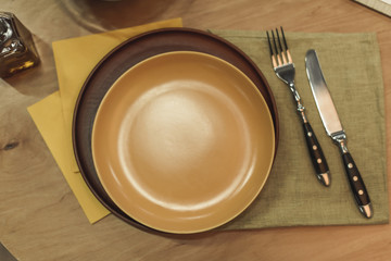 top view of empty plates, cutlery and napkins on wooden surface