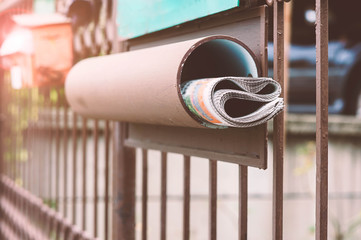The newspaper rolls in the box at the front fence.