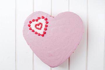 Homemade cake In the form of heart on white wooden background.