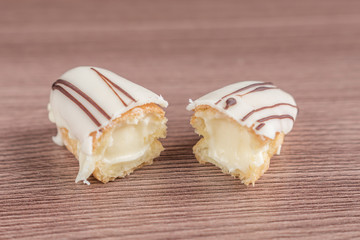 Two halves of Eclair with glaze on  a wooden table