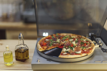 close up view of types of oil in bottles and italian pizza on vinyl record player