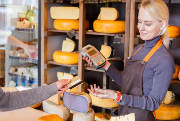 Customer paying for order of cheese in grocery shop.