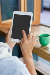 Close up of senior  woman using tablet against coffee cup