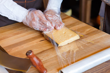 Shop assistant wrapping a piece of cheese