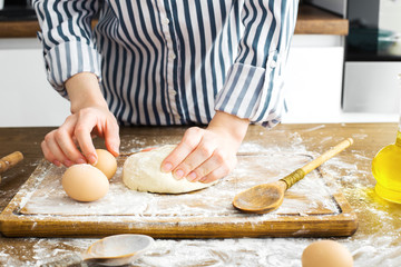 Female hands making dough on kitchen background