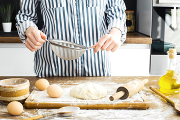 Female hands making dough on kitchen background