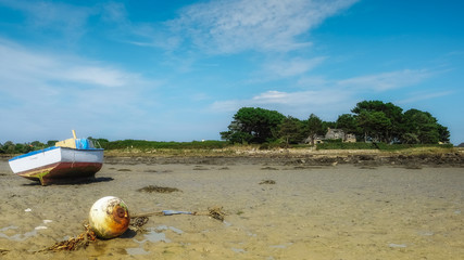 Fototapeta na wymiar Fisher boat resting in the sand near old stone house on an island