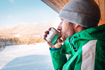 Man with cup of hot drink wqrms on open winter air
