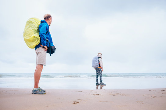 Backpacker travelers father and son  stay on ocean desret beach in rainy day
