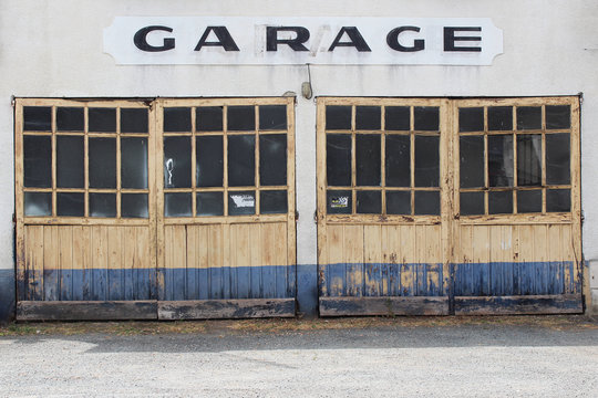 Old wooden and glass doors, painted in retro yellow and blue colours with hand painted garage sign above