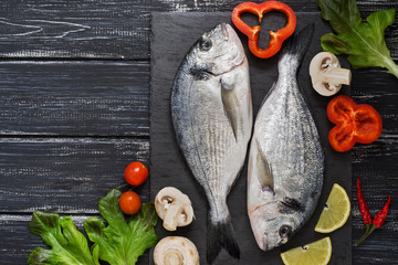 Fresh dorado fish on a slate plate with vegetables