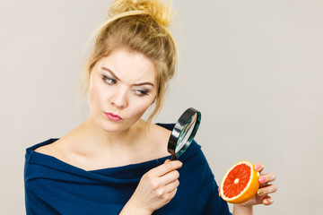 Woman holding magniferlooking grapefruit