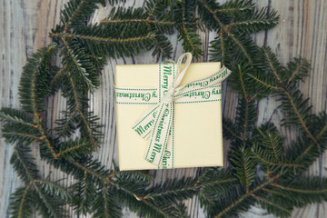 A gift box in a wreath on a light wooden shabby background