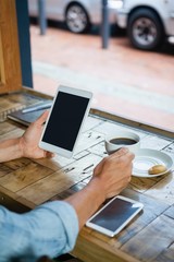 Person holding tablet computer by coffee cup at table