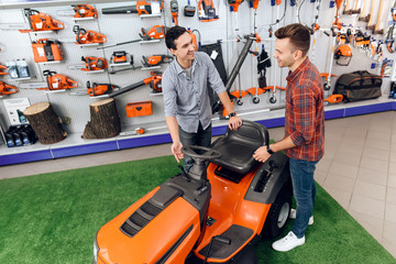 A consultant in a garden tools store shows a customer a lawn mower.