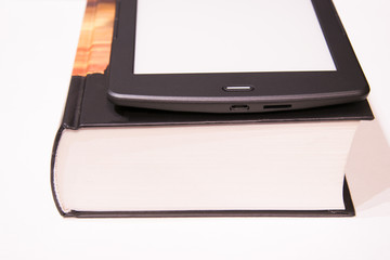Thin e-book is on a rough paper book..New paper technologies. Replacing paper books. Convenience and comfort of reading. White background. Isolated.
