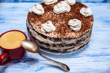 sour cream cake with cream and fresh coffee in a red mug on a light wooden background