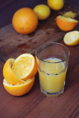 Glass of Freshly Pressed Orange Juice with Sliced Oranges on wooden table. Vertical Image.