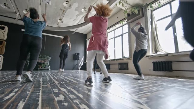 PAN of multiethnic group of happy women dancing zumba in studio and having fun