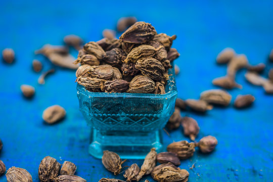 Raw black cardamom on a brownish wooden surface.