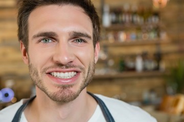 Smiling waiter standing behind the counter