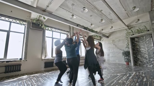 PAN with slowmo of young women doing aerobics in circle in airy studio