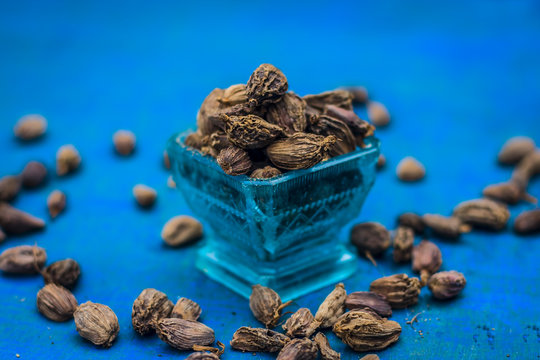Raw black cardamom on a brownish wooden surface.