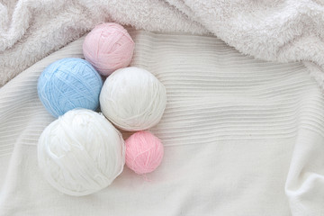 Fototapeta na wymiar pink' blue and white warm and cozy yarn balls of wool over soft bed.